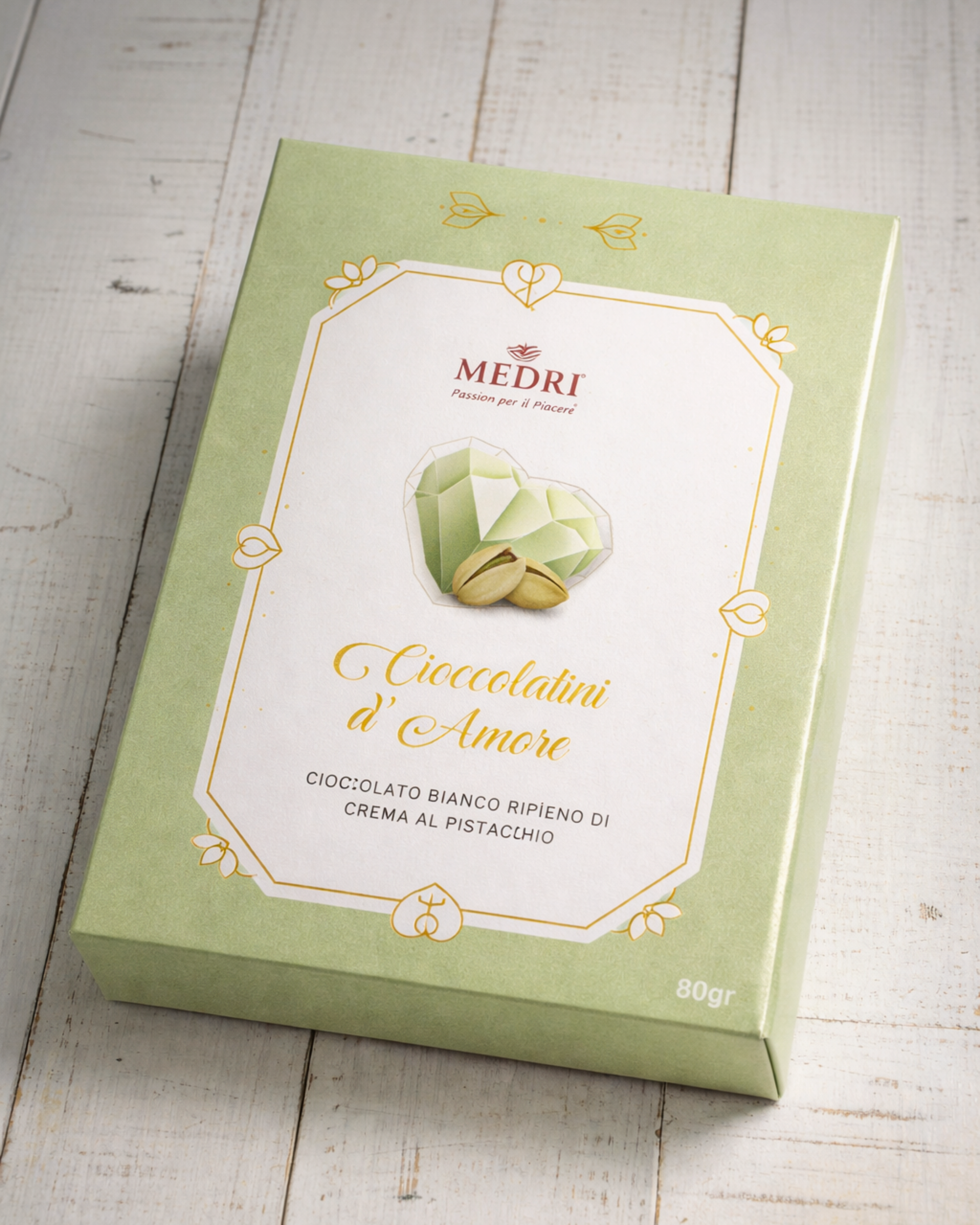 Medri Tiramisu Cafe Cioccolatini d’Amore white chocolate and pistachio bonbons, 80g, displayed on a plate with pistachios.