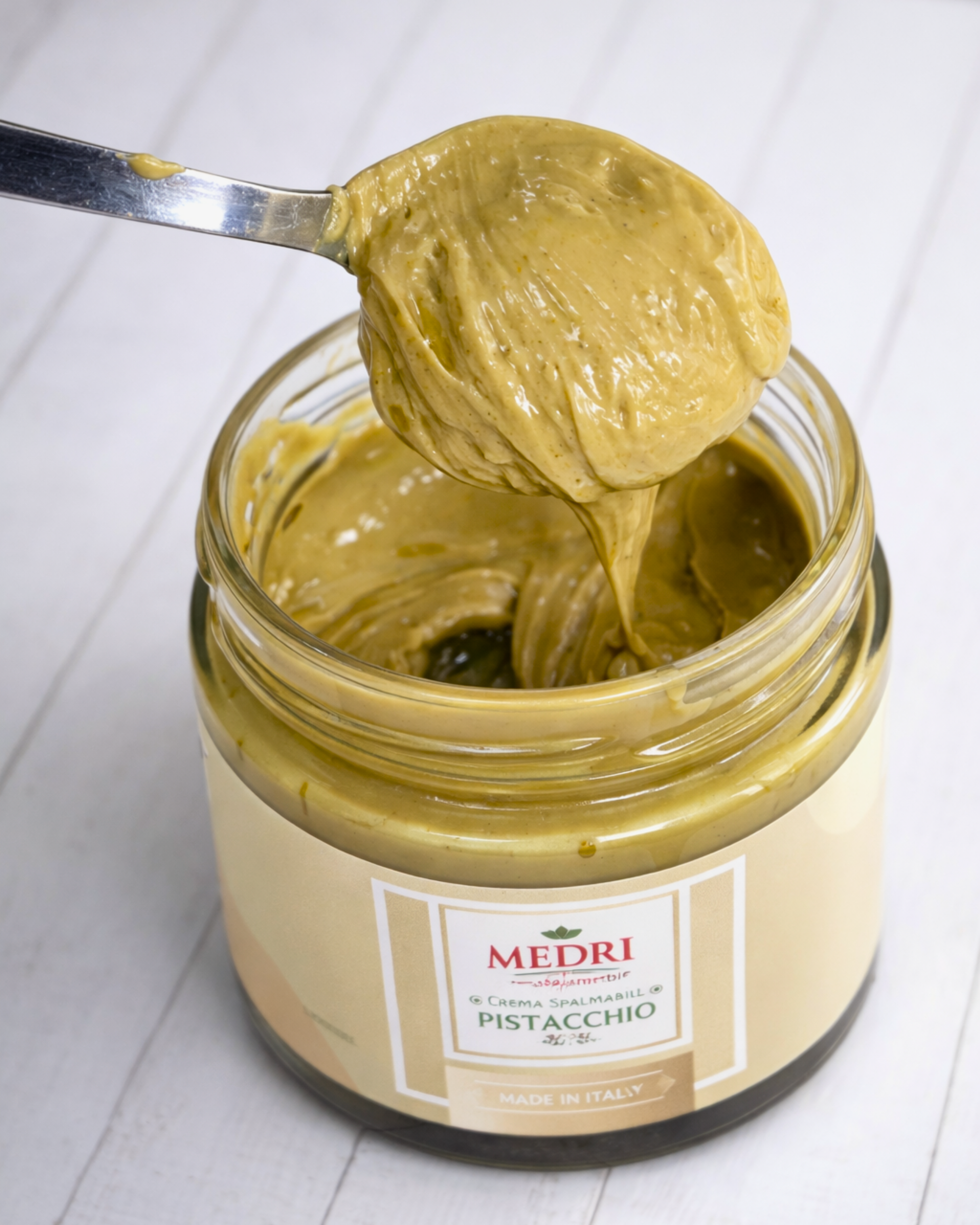 Creamy pistachio spread with 25% pistachio content from Medri Tiramisu Cafe, shown in a jar with a smooth texture.