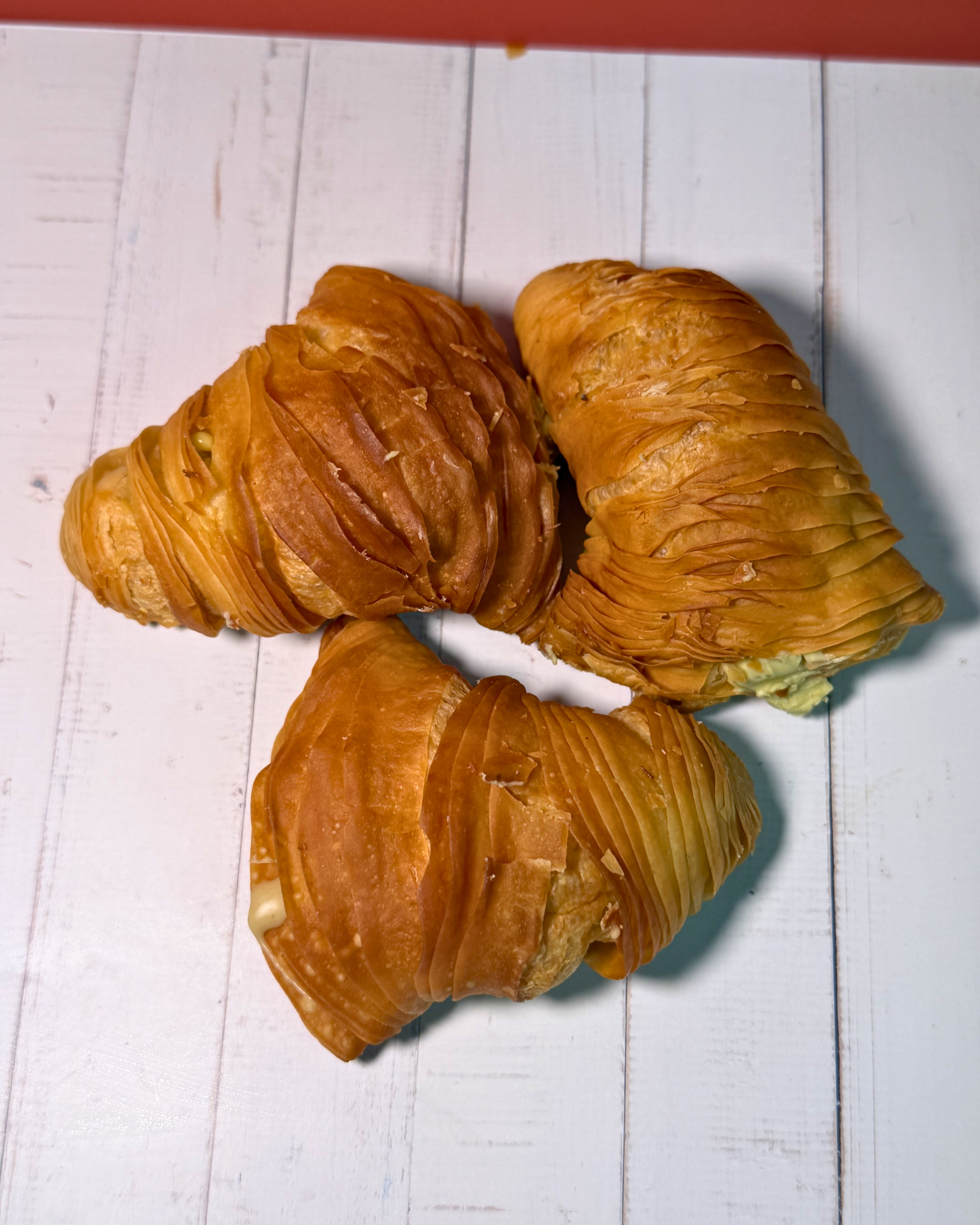 Golden pistachio sfogliatella pastry by Medri with flaky layers and pistachio filling, displayed on a white plate.