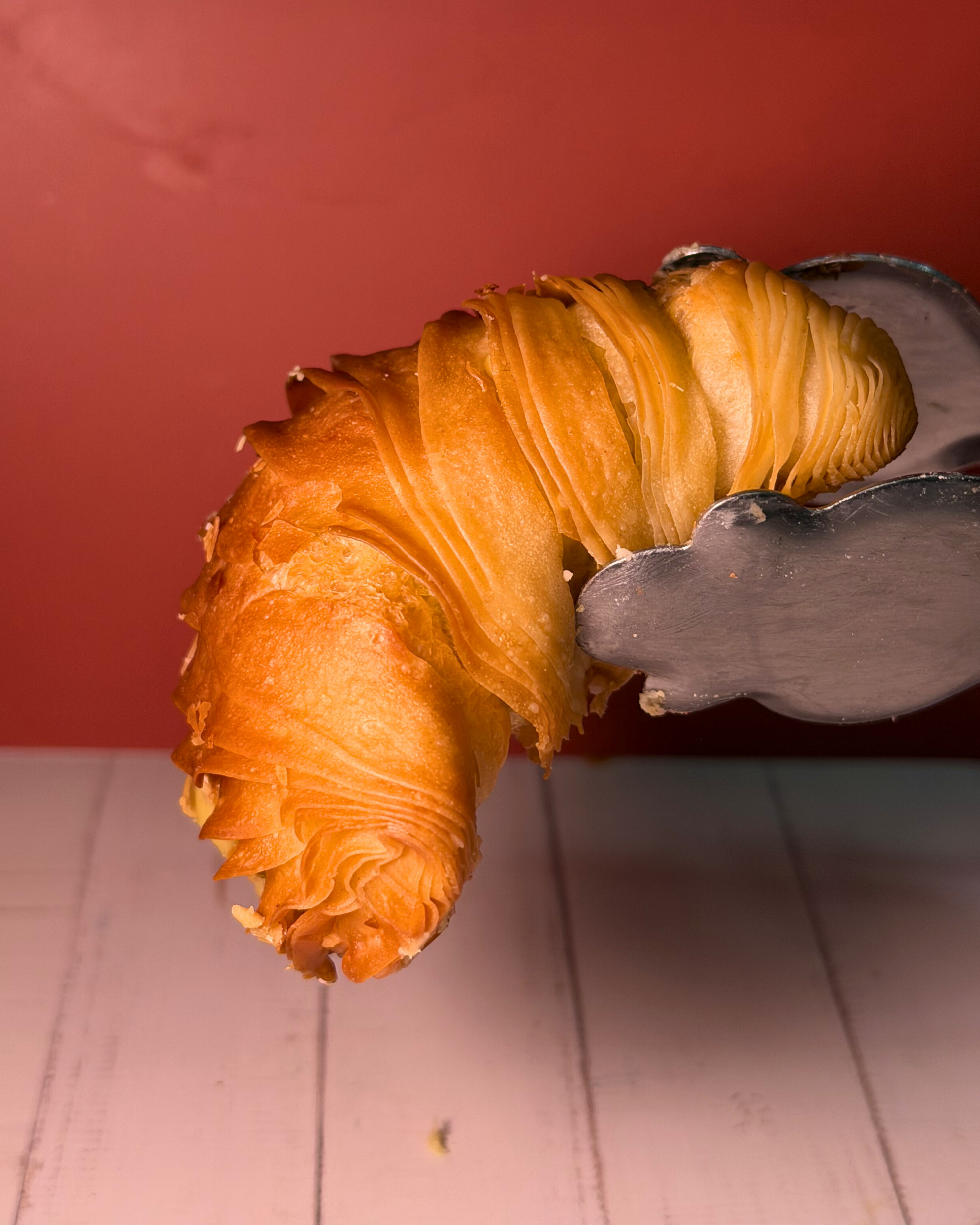 Golden pistachio sfogliatella pastry by Medri with flaky layers and pistachio filling, served on a white plate.